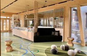 Foyer des March-Thaya-Zentrums, © Ruth Trinkler Innenansicht eines modernen Foyers mit Holzelementen, einer Sitzbank und dekorativen Steinen auf dem Boden.