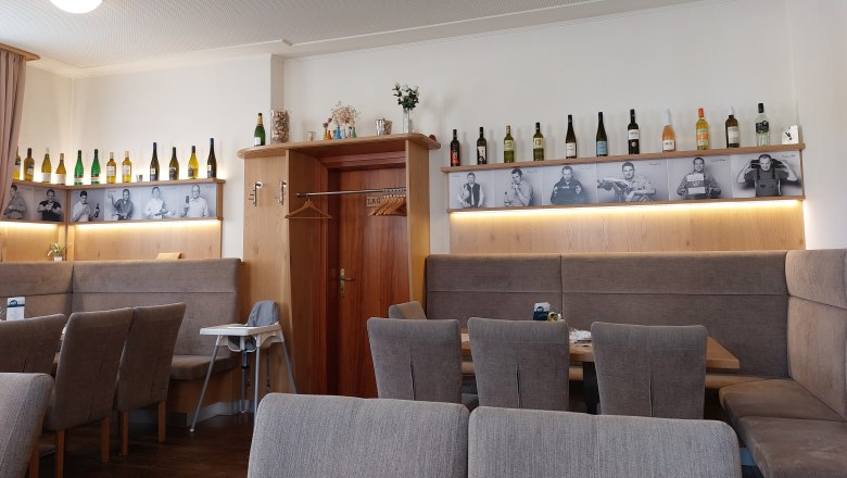 Gaststube, © Weinviertel Tourismus Innenansicht eines Restaurants mit Weinflaschen und Schwarz-Weiß-Fotos an der Wand.