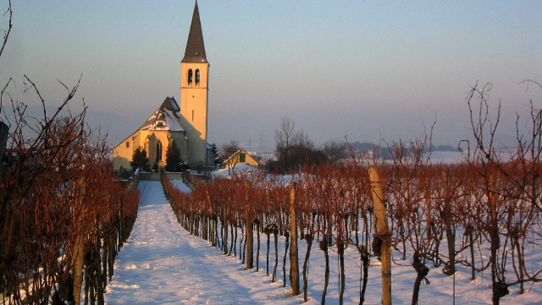 Kirche im Winter, © Gemeinde Stetten Kirche im Winter mit schneebedecktem Weg und kahlen Weinreben.
