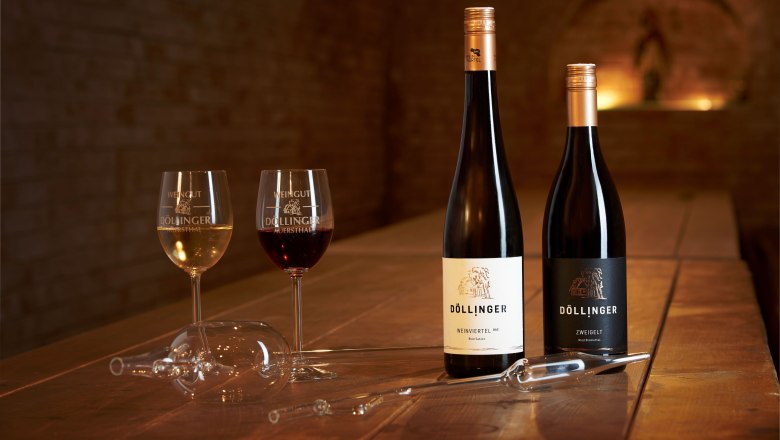 Weingenuss, © Markus Lang-Bichl Zwei Weingläser und zwei Flaschen Wein auf einem Holztisch in einem Weinkeller.