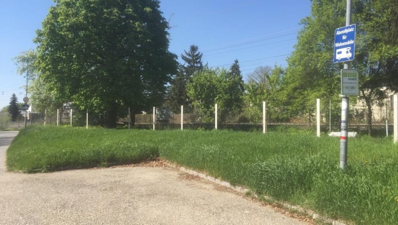 wohnmobilstellplatz-alte-au-stockerauklein, © Roland Richentsky Wohnmobilstellplatz mit Schild, umgeben von Bäumen und Gras.