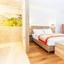 TDR-Hopfeld Dreikönigshof-Genuss.Zimmer, © flotographix -Kampl Florian Modernes Hotelzimmer mit Doppelbett, orangefarbenem Sessel und offener Dusche.