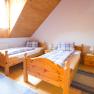 Zimmer mit getrennten Betten, © Winzerhof Semmler Gemütliches Schlafzimmer mit zwei Einzelbetten aus Holz, blauen Teppichen und einem Fenster mit Holzverkleidung.