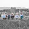 TDR-Hopfeld-Dreikönigshof, © ehnpictures- Johannes Ehn Eine Gruppe von sechs Personen in traditioneller Kleidung steht auf einem Feld mit einer Burg im Hintergrund.