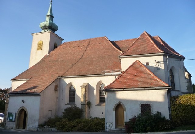 Eine historische Kirche mit einem roten Ziegeldach und einem kleinen Turm mit gr&uuml;nem Dach.