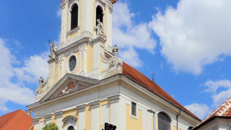Barocke Kirche mit Turm und Uhr vor blauem Himmel.