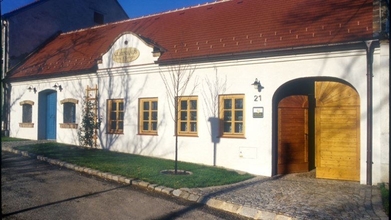Weißes Gebäude mit rotem Dach und Holztüren, beschriftet mit 'Kleinhaus'.