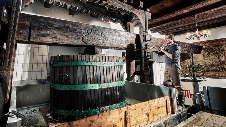 Ein Mann arbeitet an einer traditionellen Weinpresse in einem Weingut.