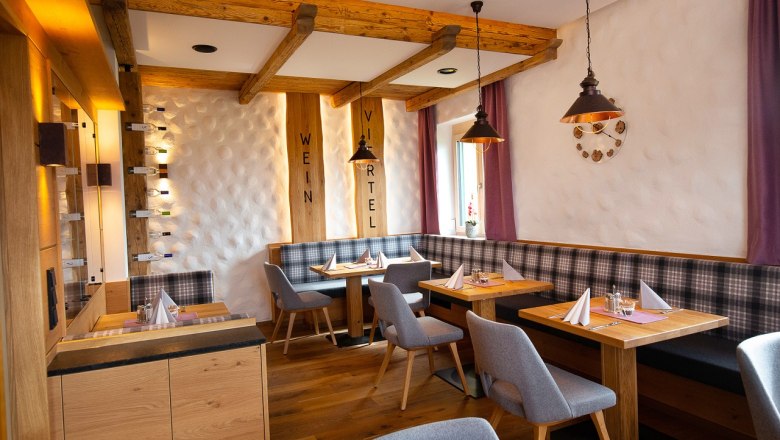 Gem&uuml;tliches Restaurant mit Holzm&ouml;beln, gedeckten Tischen und lila Vorh&auml;ngen.