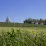 Landschaft mit Kapelle, Weinbergen und H&auml;usern unter blauem Himmel.