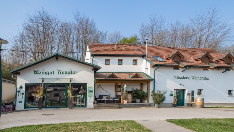Weingut K&uuml;ssler mit Weinbar und Terrasse, umgeben von B&auml;umen.