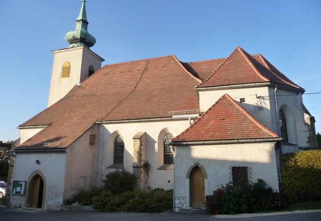 Historische Kirche mit rotem Ziegeldach und kleinem Turm mit gr&uuml;nem Dach.