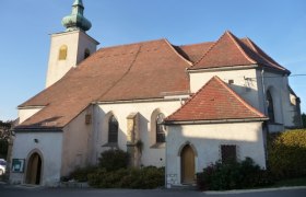 Historische Kirche mit rotem Ziegeldach und kleinem Turm mit gr&uuml;nem Dach.