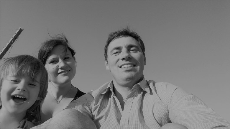 Schwarz-weiß Foto einer lächelnden Familie, bestehend aus einem Mann, einer Frau und einem Kind, die in die Kamera schauen.