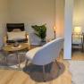 Gemütliches Schlafzimmer mit Sessel, Tisch, Pflanze und Bett.