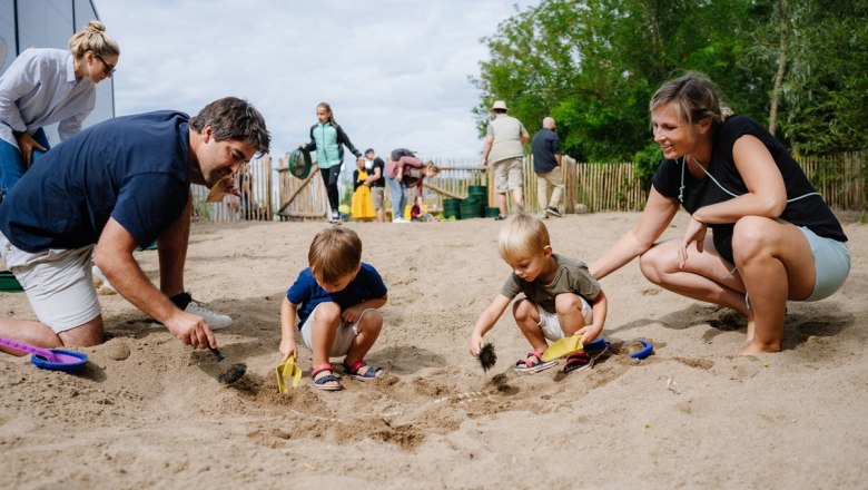Familien graben im Sand nach Fossilien in einem Freilichtmuseum.