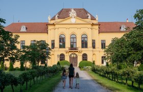 Frau mit zwei M&auml;dchen an der Hand geht auf einem Schotterweg Richtung Schloss Eckartsau.