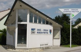 Gebäude des Erdöl-Erdgas Museums Prottes mit Wegweiser.