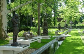 Skulpturen im Park von Bad Pirawarth, umgeben von B&auml;umen und einem kleinen Wasserlauf.