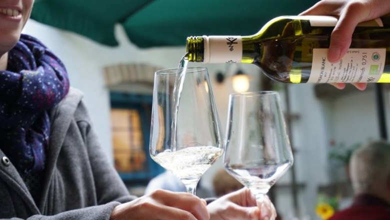 Wein wird in ein Glas gegossen, während eine Person es hält.