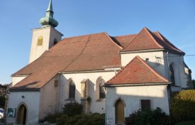 Eine historische Kirche mit einem roten Ziegeldach und einem kleinen Turm mit gr&uuml;nem Dach.