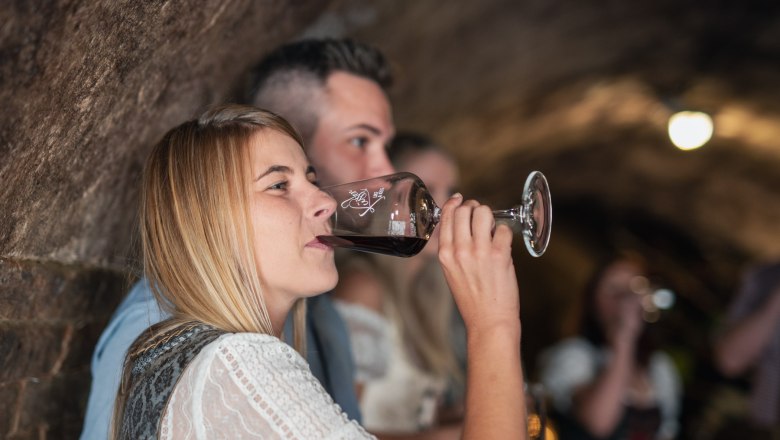 Frau trinkt Wein in einem Weinkeller.