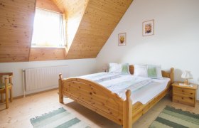 Gemütliches Schlafzimmer mit Holzmöbeln und Dachschräge.