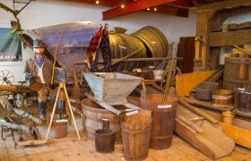 Ausstellung mit alten landwirtschaftlichen Ger&auml;ten und Holzf&auml;ssern.