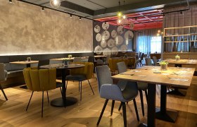 Modernes Restaurant mit stilvoller Einrichtung, Holztischen und gemütlichen Stühlen.