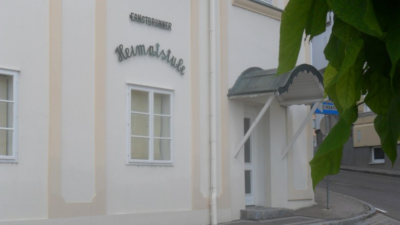 Eingang zur Ernstbrunner Heimatstube mit Vordach und Stra&szlig;enschild.