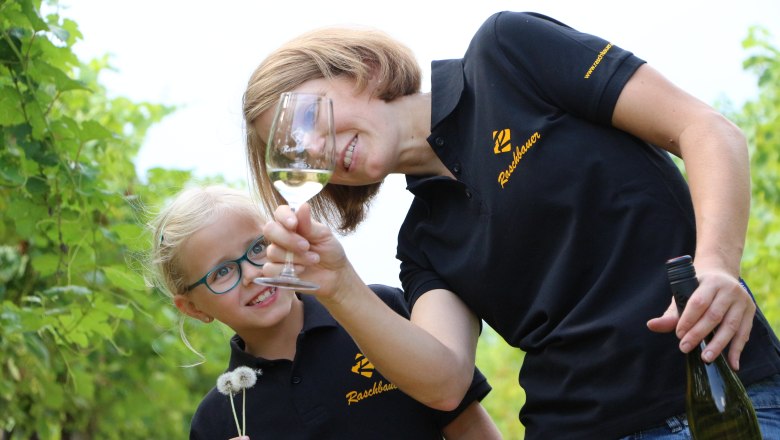 Frau und Kind im Weinberg mit Weinglas und Pusteblume.