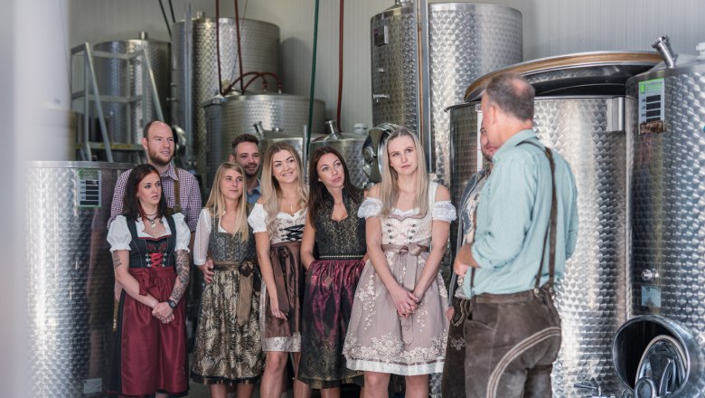Gruppe von Menschen in traditioneller Kleidung in einer Brauerei.