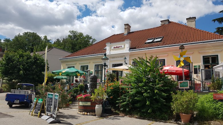 Au&szlig;enansicht von Buchingers Gasthaus Zur Alten Schule mit Terrasse und Sonnenschirmen.